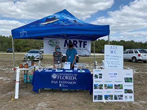 A blue-tented booth with signage for both UF/IFAS and the Fort Myers Beach marine resource task force