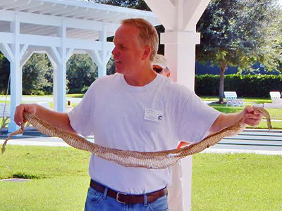 Jim Davis holding snake skin during an outside demonstration
